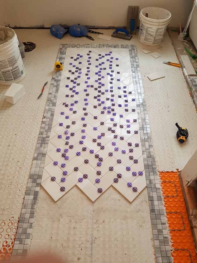 A tile floor is being installed in a bathroom.