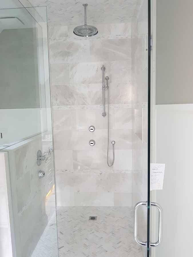 A bathroom with a walk in shower and a glass door.