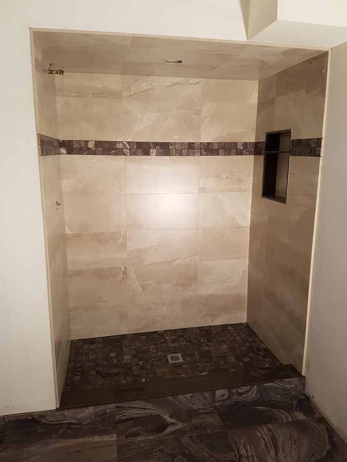 A bathroom with a walk in shower and a tiled floor.
