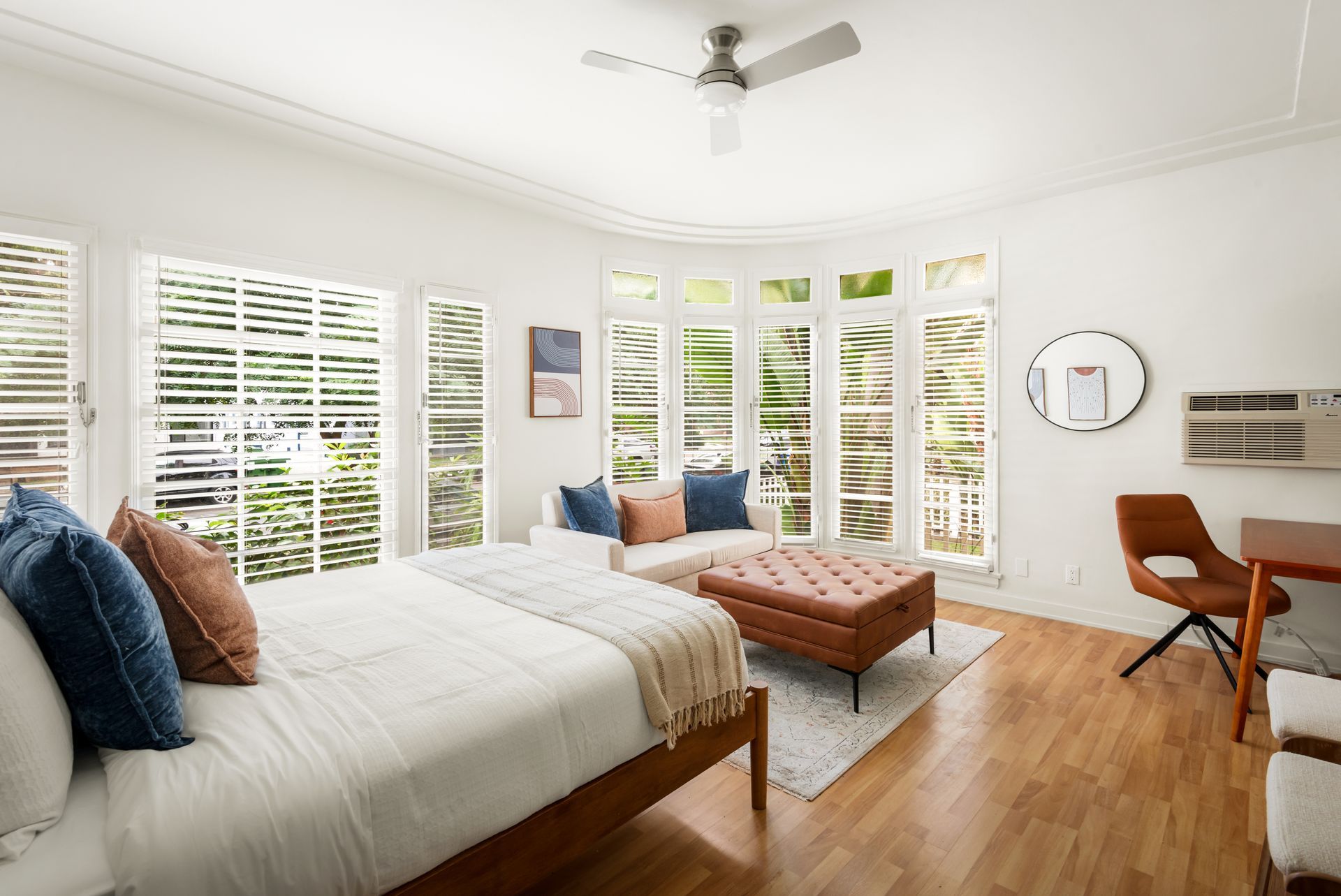 Bedroom with bed, seating area, large windows, and desk.