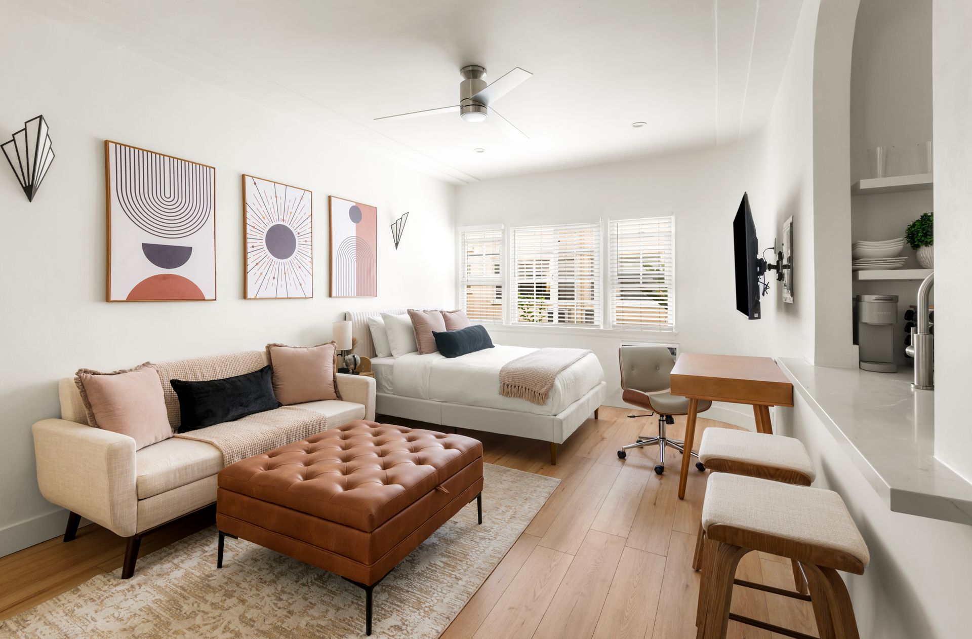 Bright studio apartment with a couch, bed, desk, and decorative art.