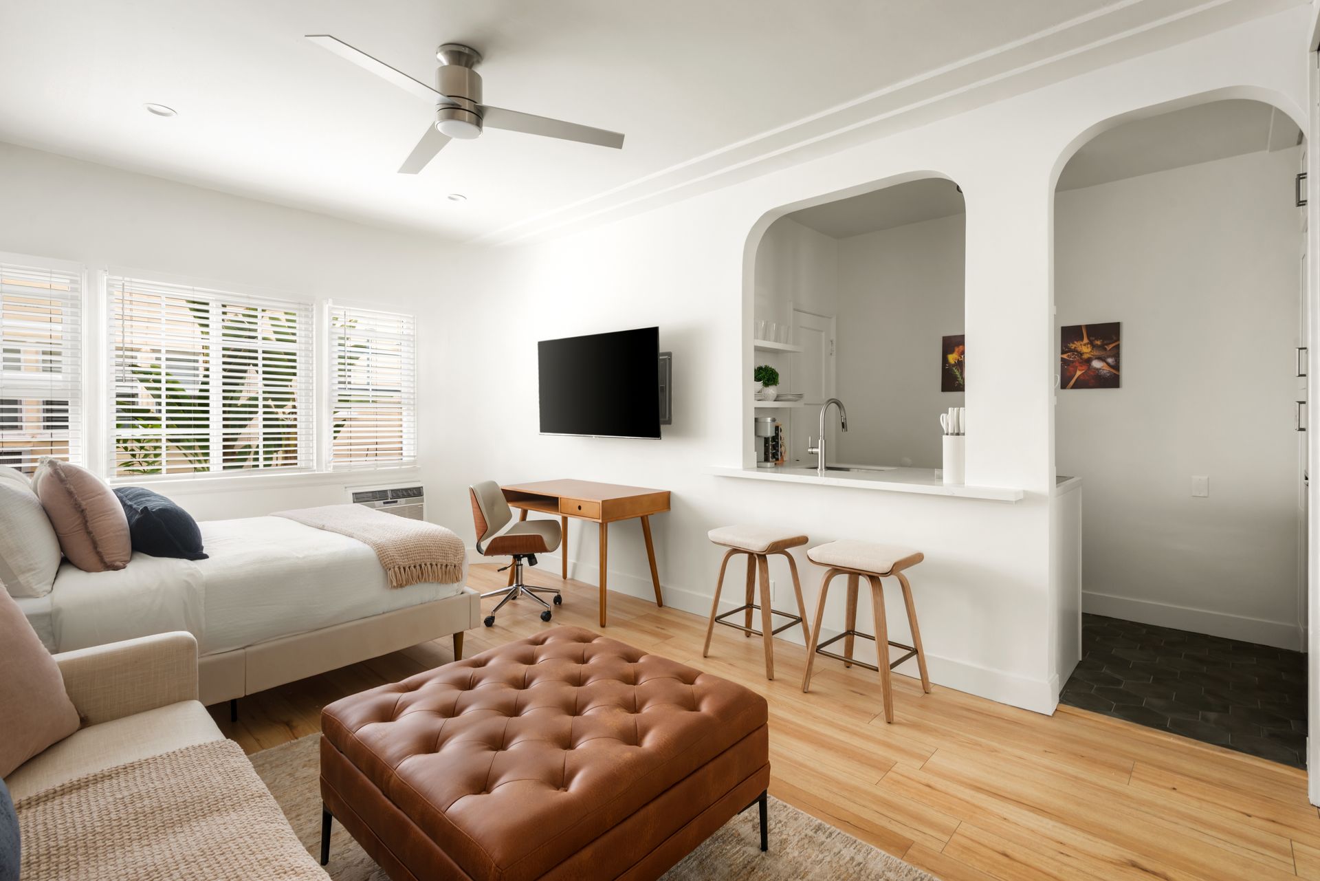 Bright living space with sofa, TV, desk, and kitchen pass-through.