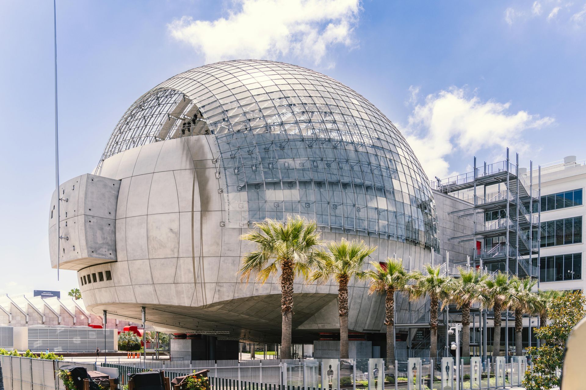 Exterior view of Academy Museum of Motion Pictures with a large dome, palm trees, and a blue sky.