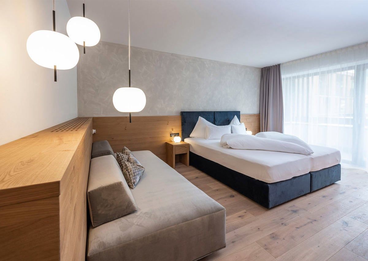 Moderna camera d'albergo con letto, divano letto e illuminazione decorativa.
