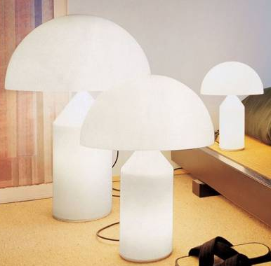 Lampade bianche a forma di fungo di diverse dimensioni, che emanano una luce soffusa, in un ambiente interno moderno.