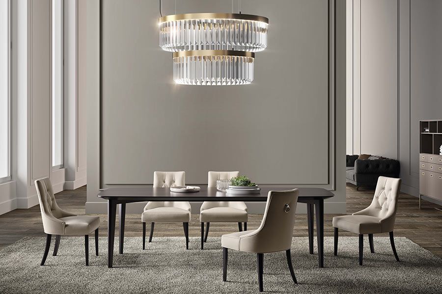 Sala da pranzo con tavolo, sedie, tappeto e lampadario a più livelli.