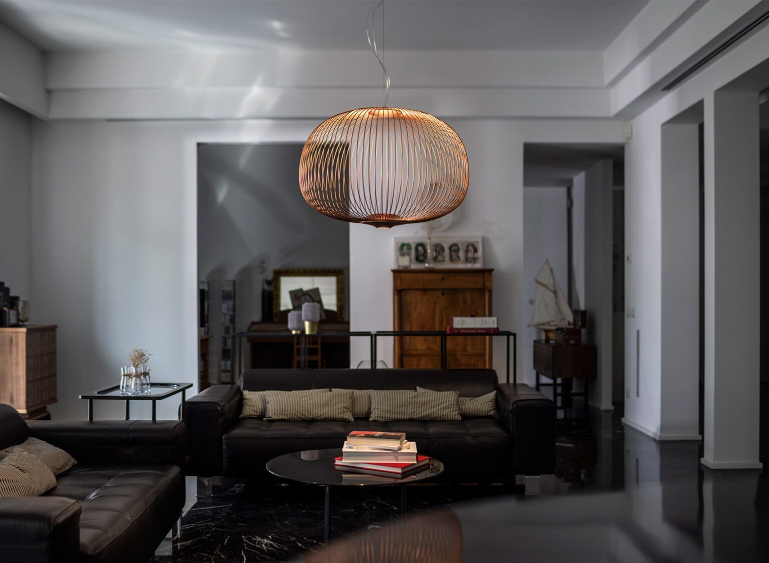 Soggiorno con mobili in pelle nera, lampada decorativa e tavolino laterale in legno.