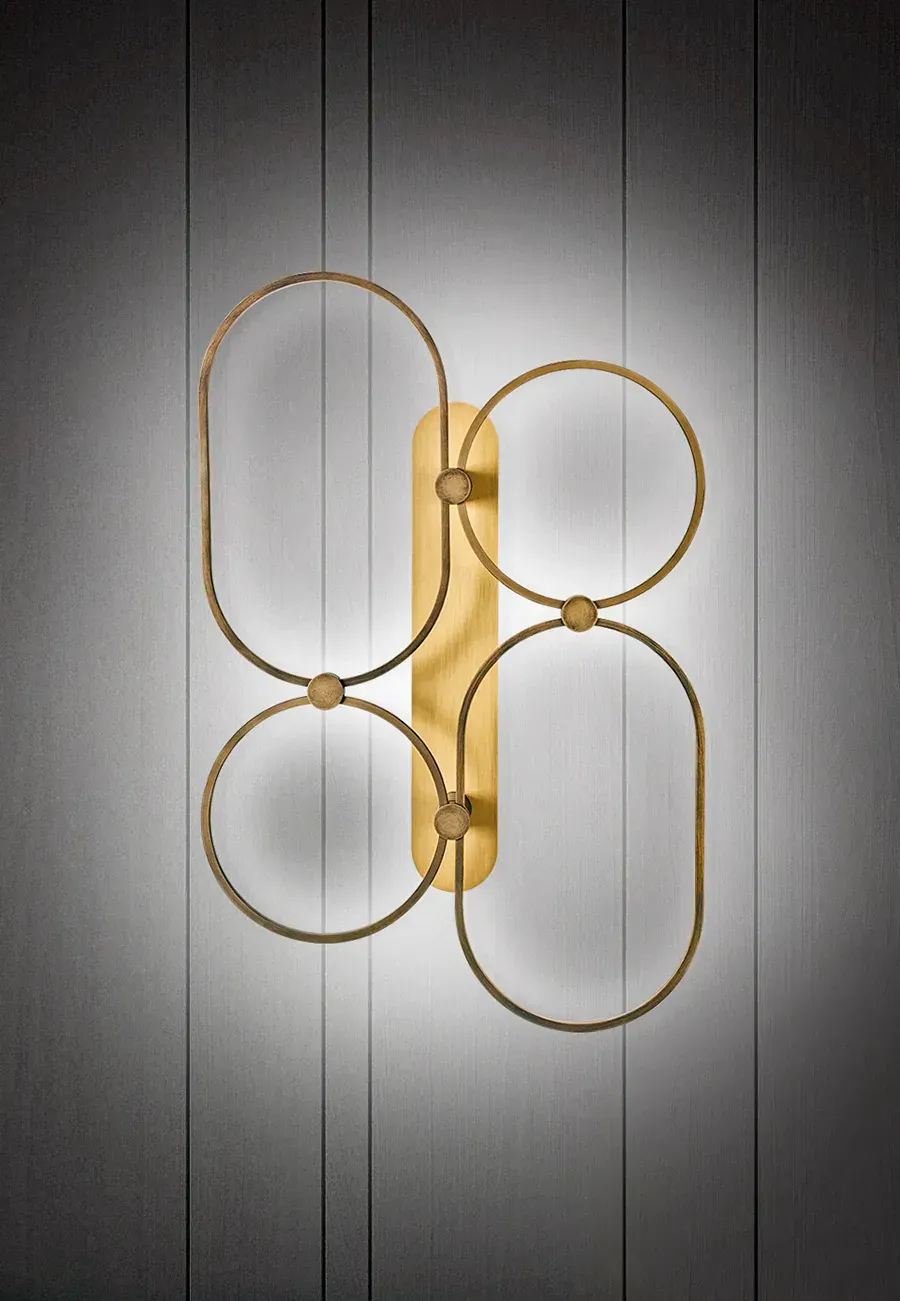 Applique da parete color oro con pannello verticale centrale e quattro forme geometriche interconnesse.