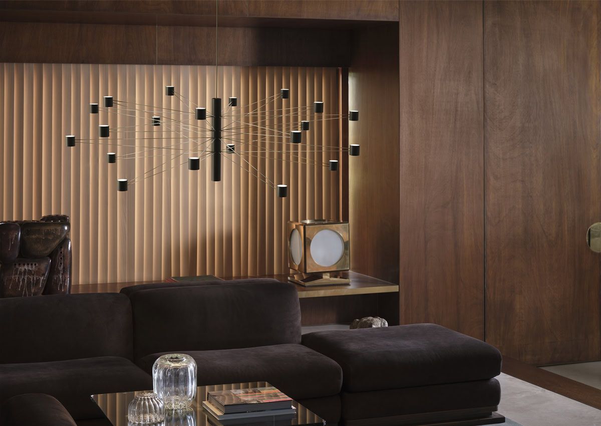 Un soggiorno moderno e scuro con un divano componibile marrone e decorazioni murali in legno.