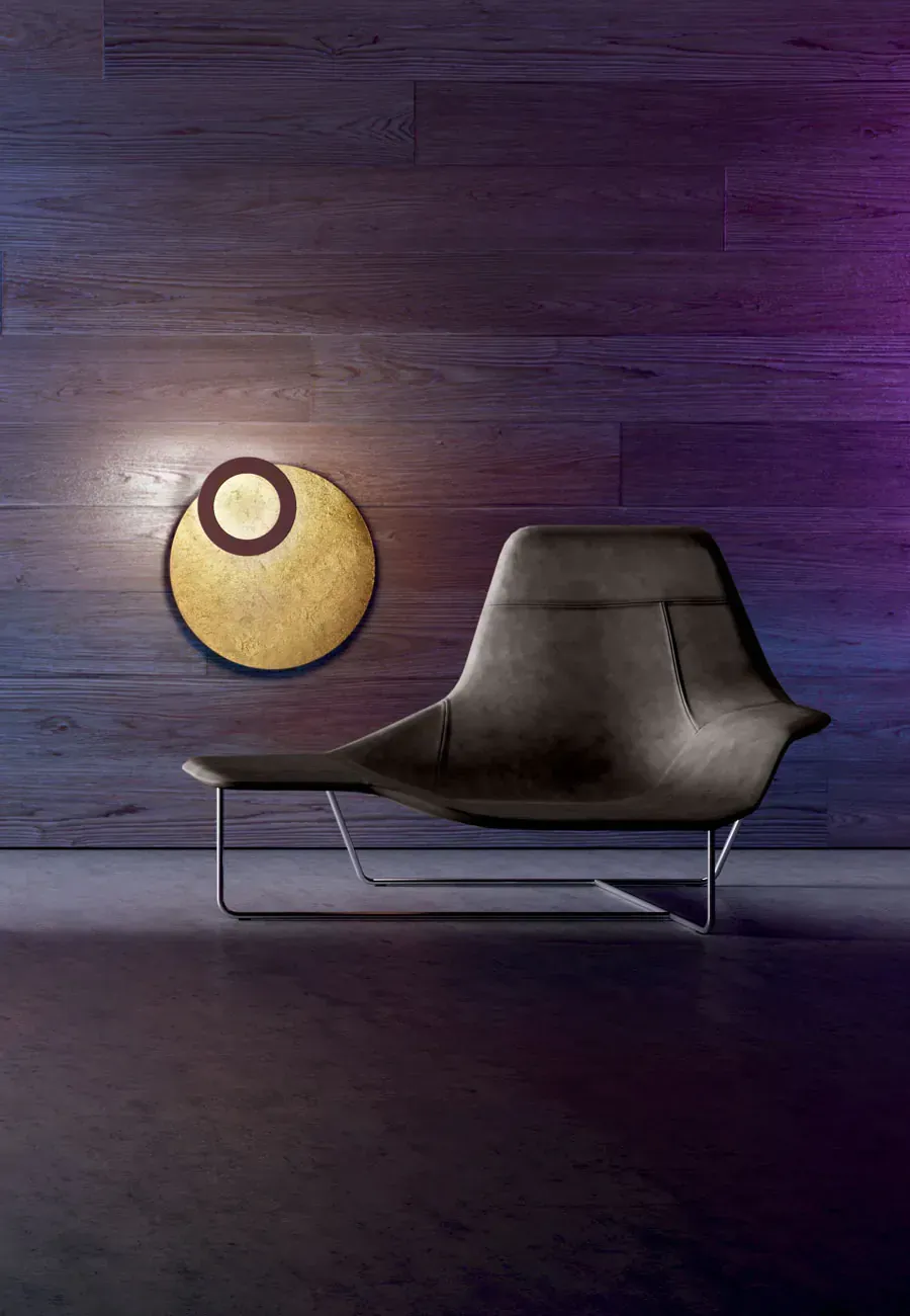 Sedia moderna nera sotto una lampada da parete circolare su una parete strutturata.