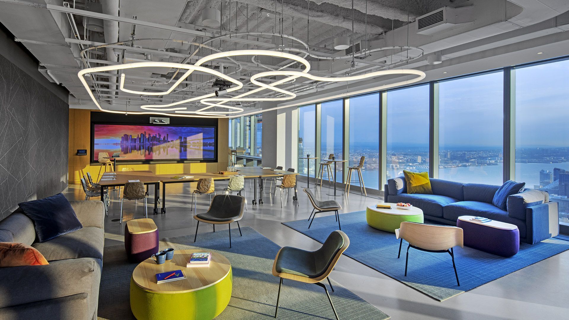 Moderna sala d'attesa per ufficio con divani, tavoli rotondi e vista sullo skyline della città.