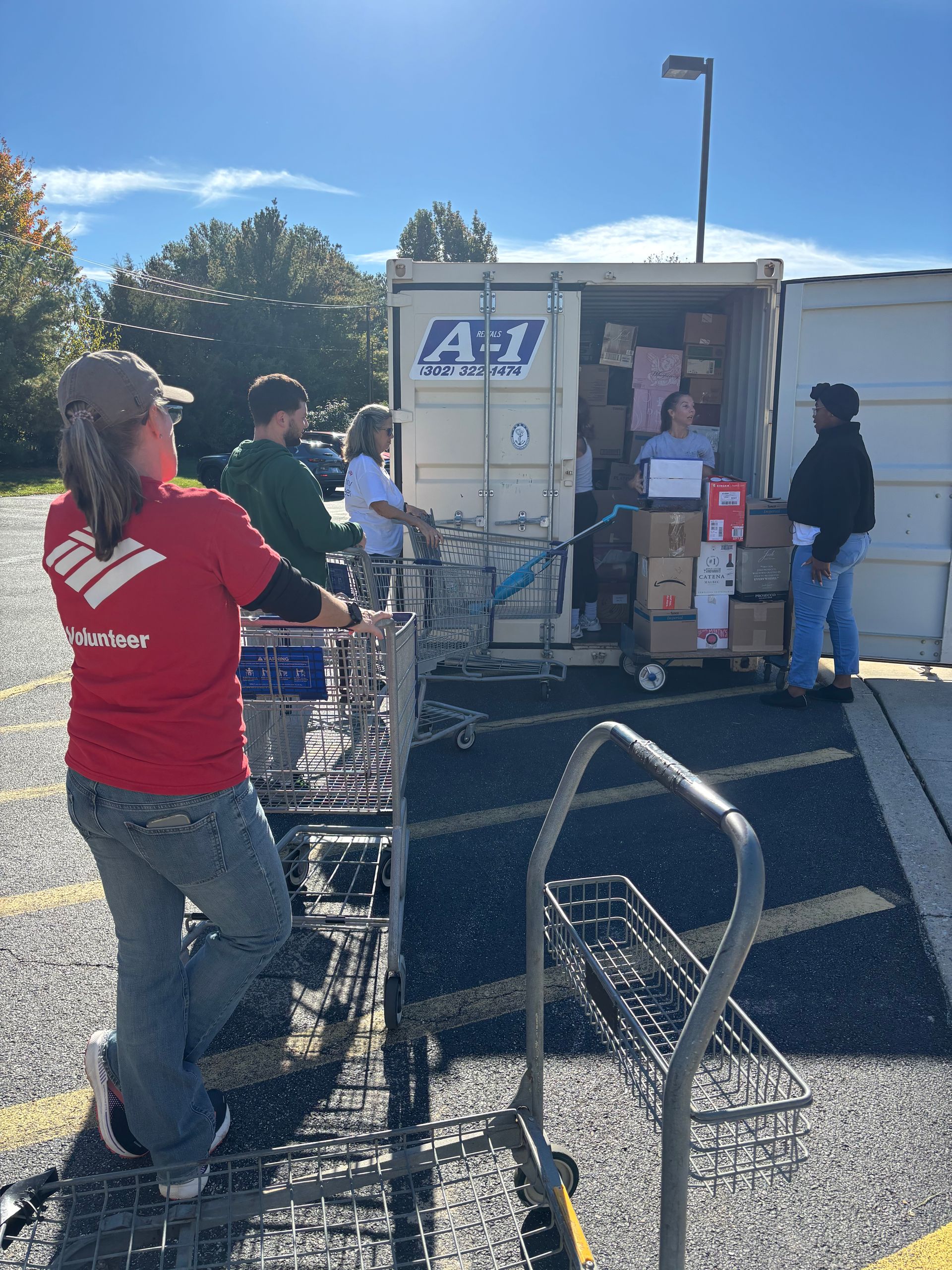 Volunteers in a parking lot load boxes and goods into an A1 shipping container.