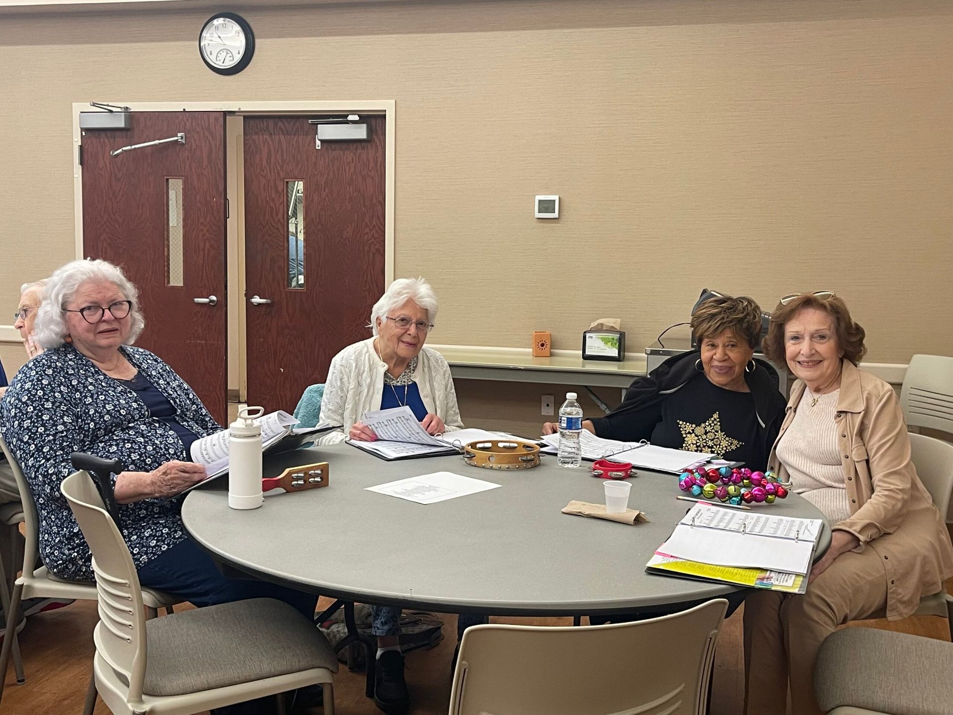 Four people sit at a round table in a meeting room, looking at documents and smiling at the camera.
