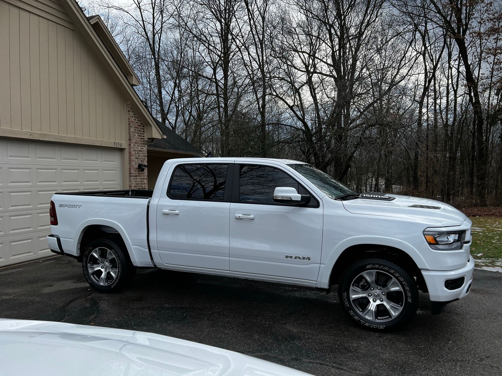 A white ram 1500 truck is parked in front of a garage.