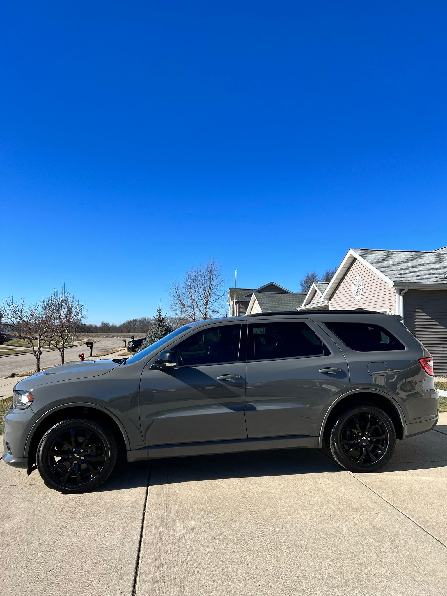 A gray suv is parked in a driveway in front of a house.
