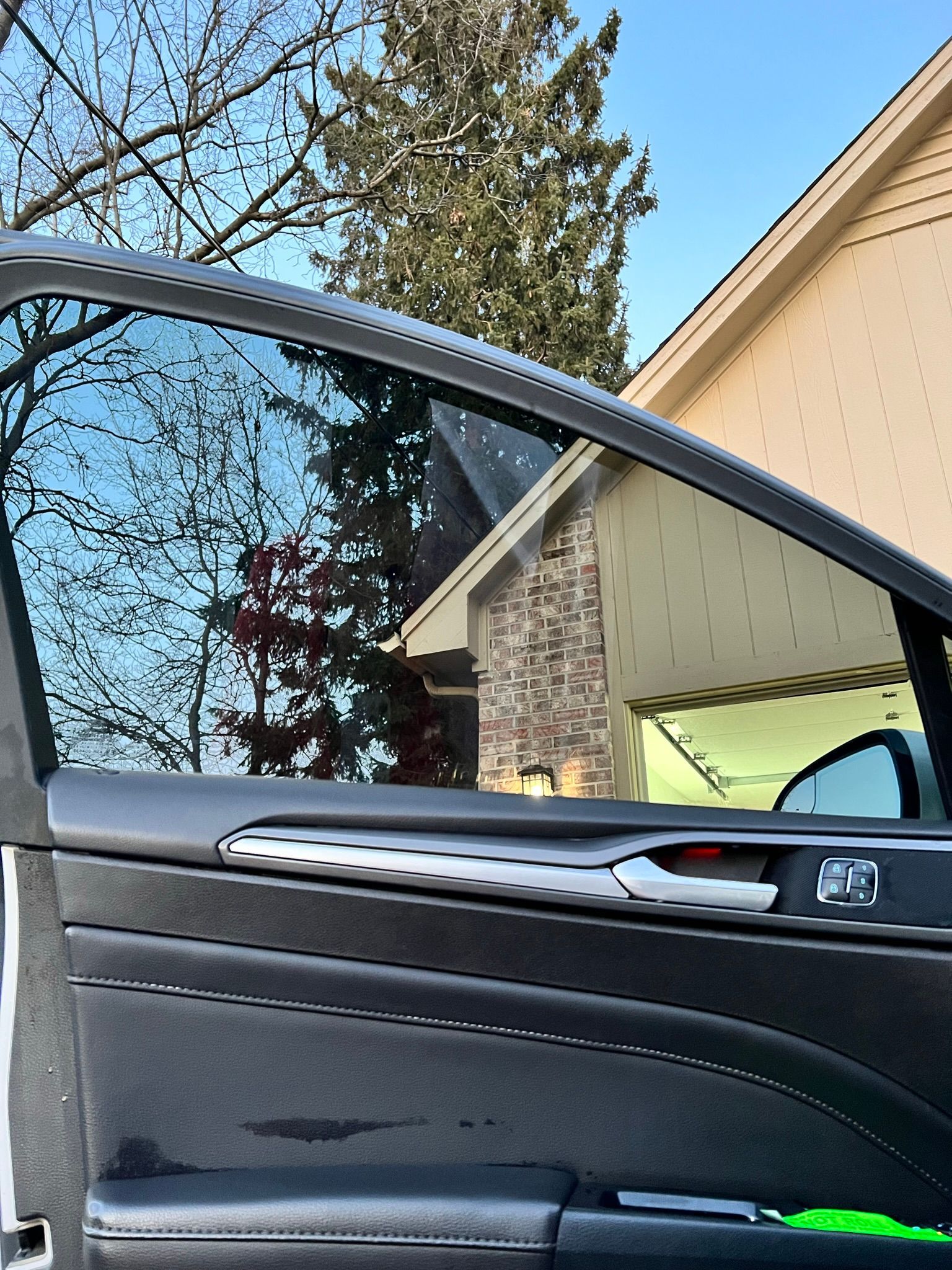 A car is parked in front of a house with the door open.