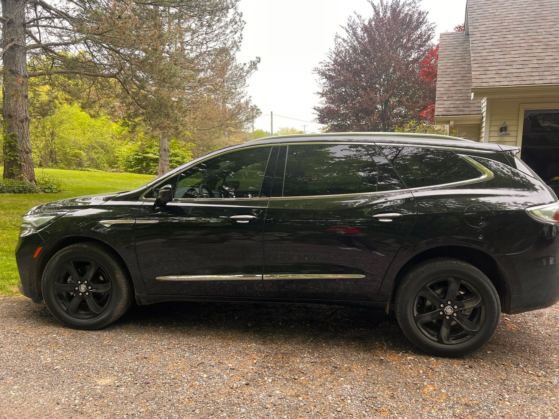 A black suv is parked in front of a house.