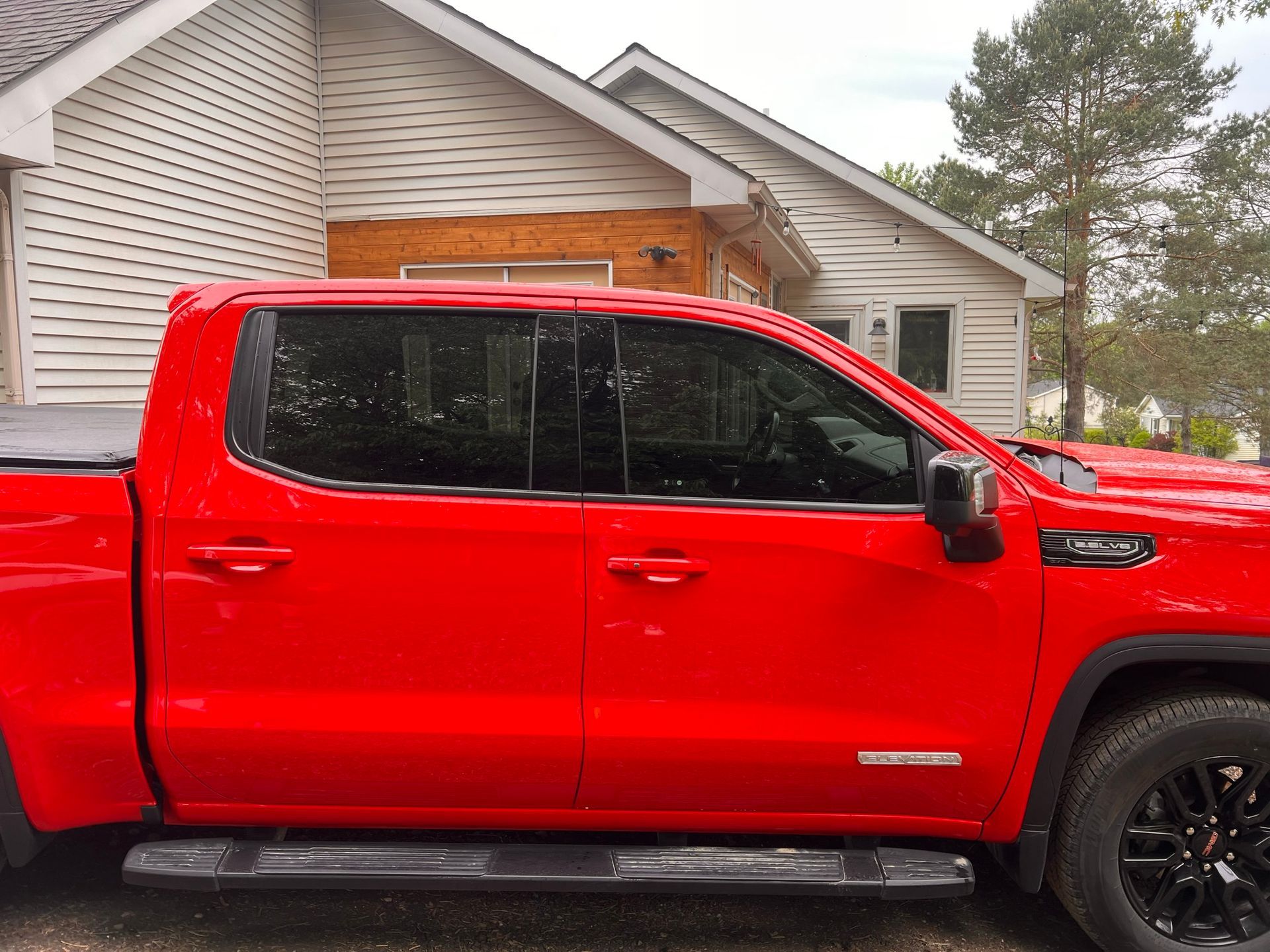 A red truck is parked in front of a white house.