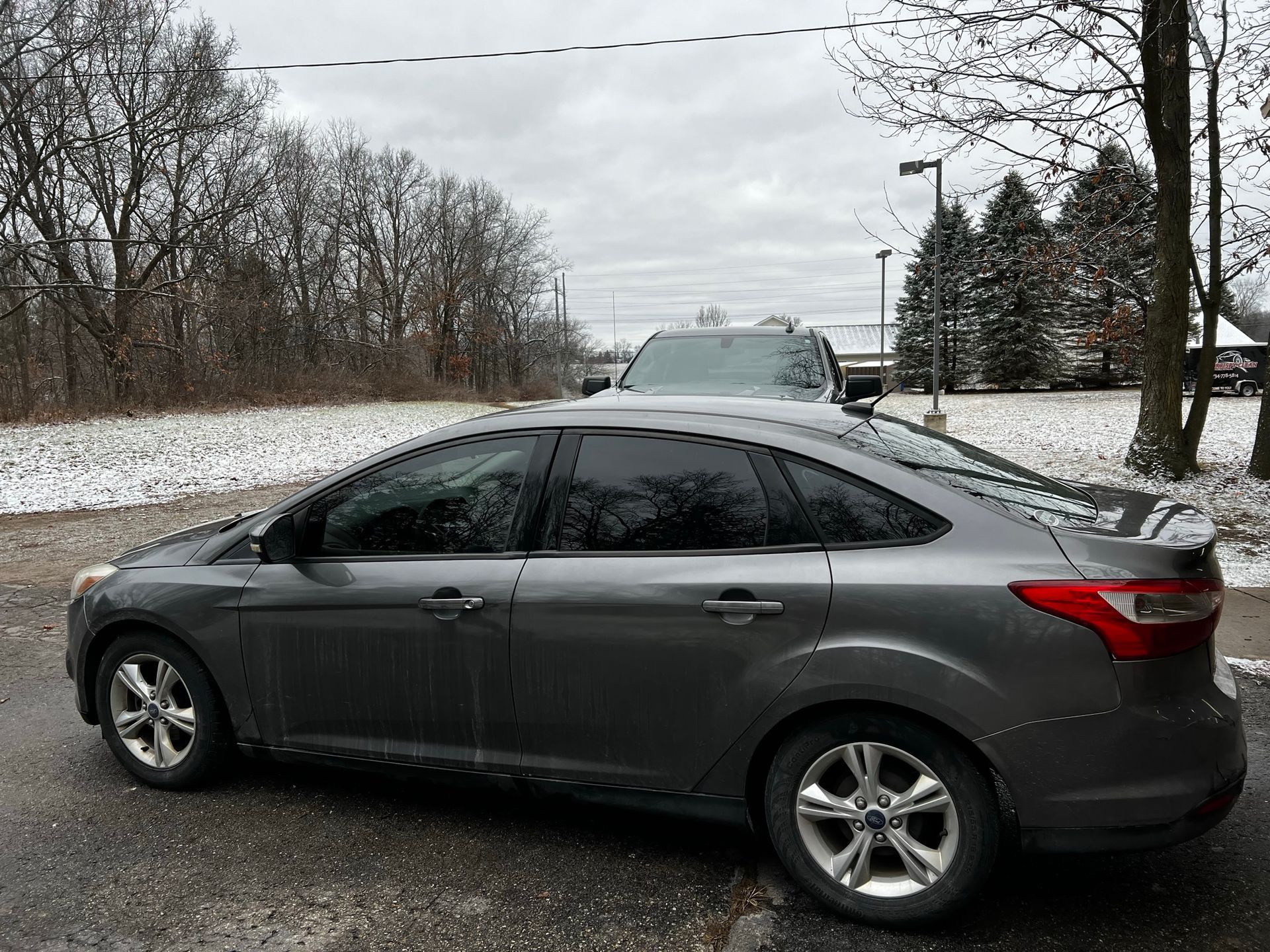 A gray ford focus is parked in a snowy parking lot.