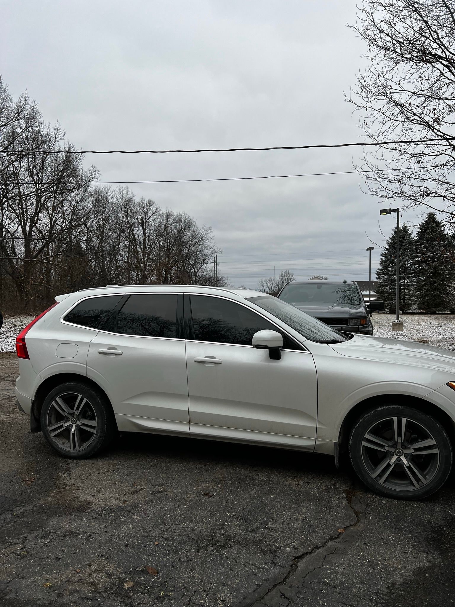 A white volvo xc60 is parked in a parking lot.