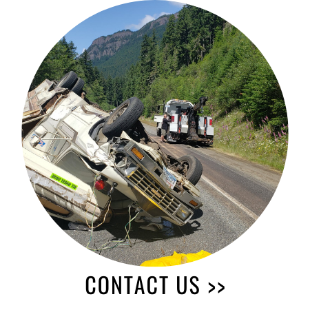 Overturned vehicle being towed on a mountain road; 