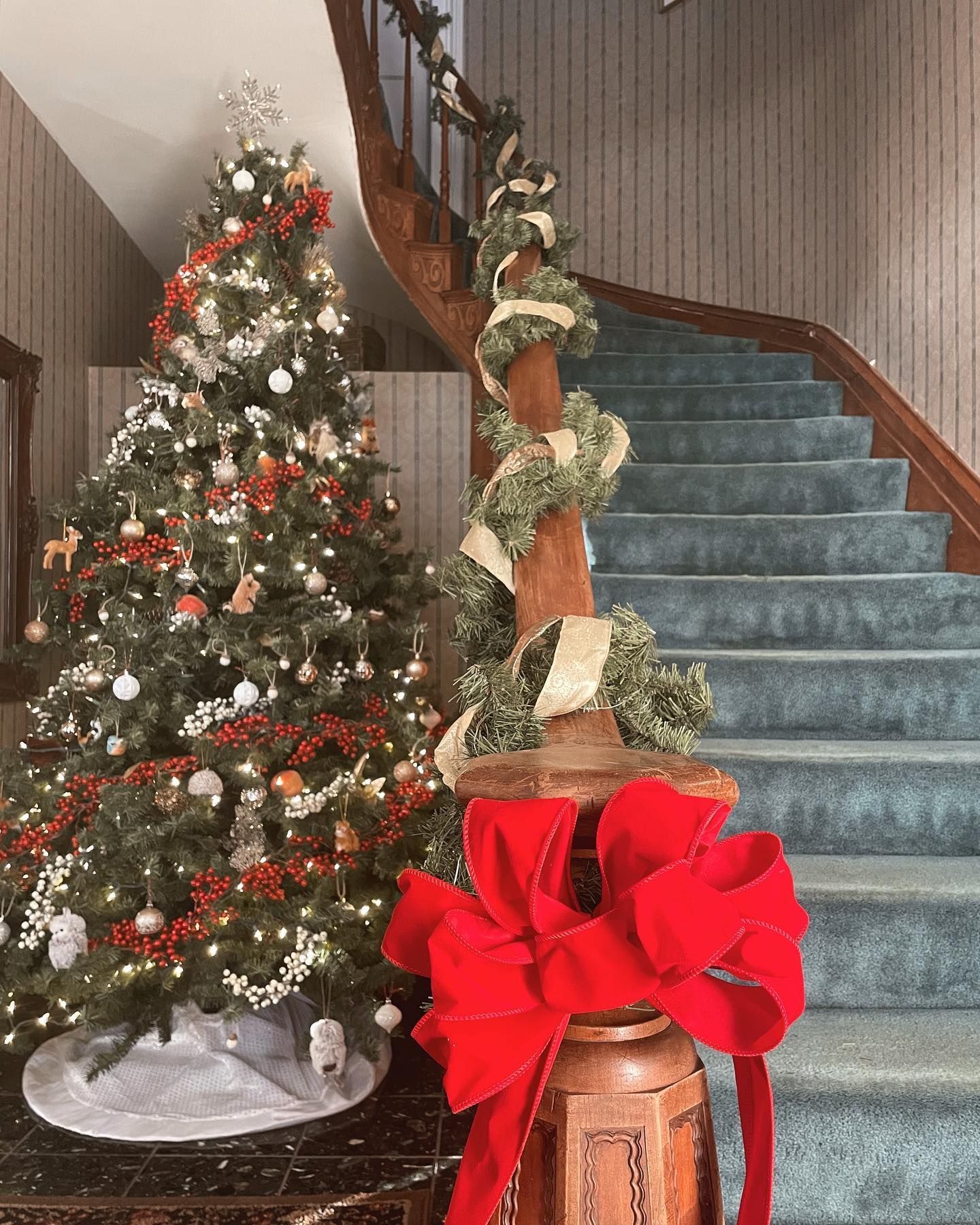Christmas tree and staircase decorated with red and white, interior setting.