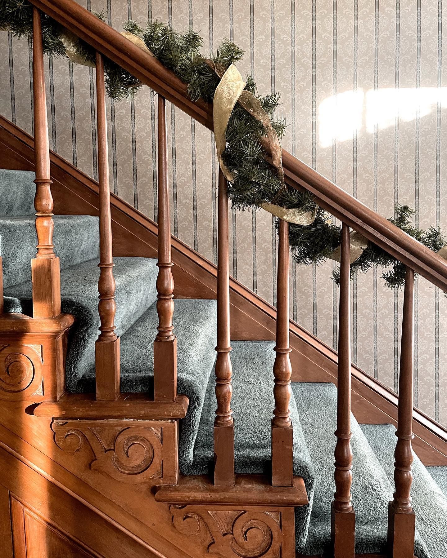 Wooden staircase with blue carpet and Christmas garland.