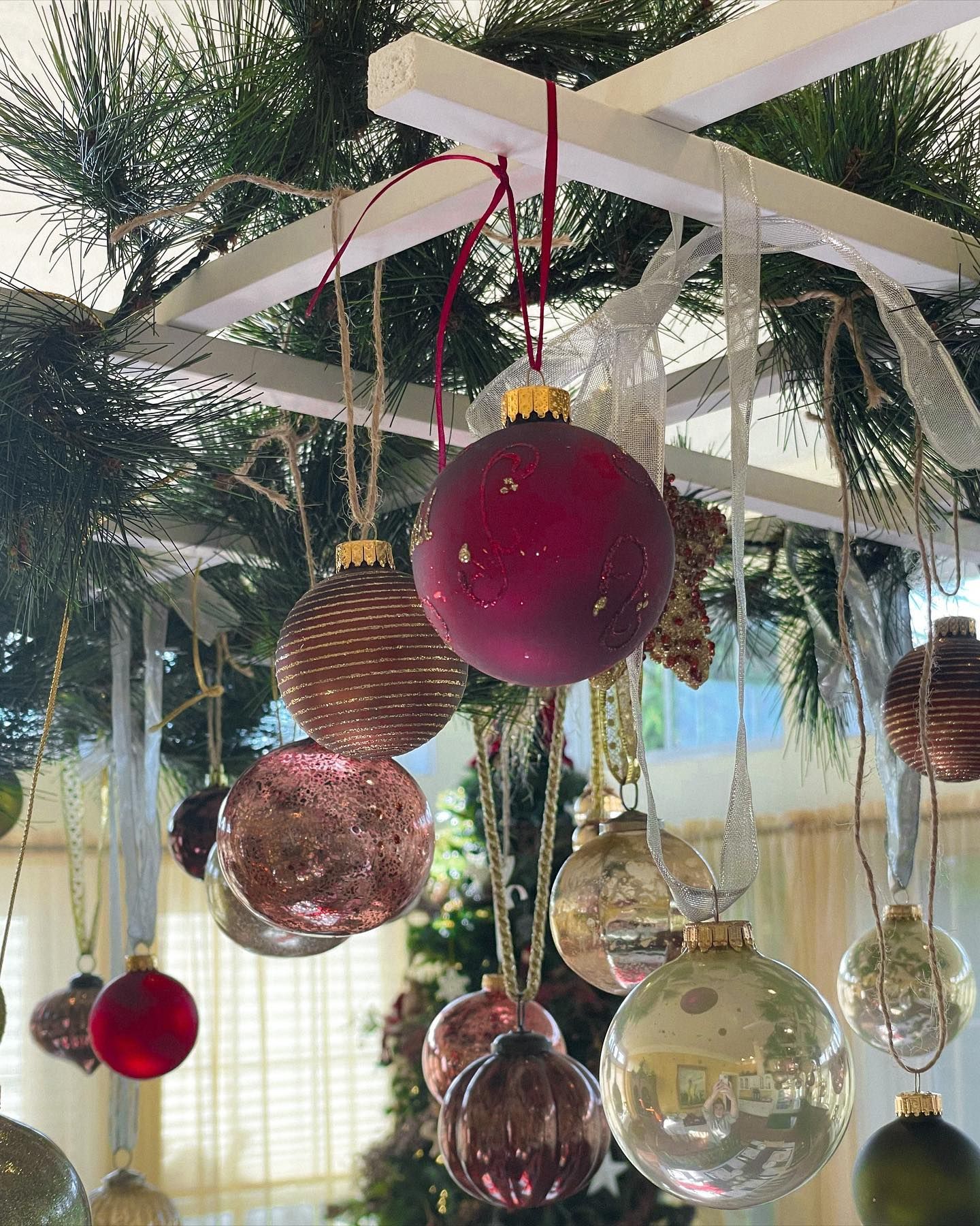 Christmas ornaments hanging from a white lattice, some with sparkly details.