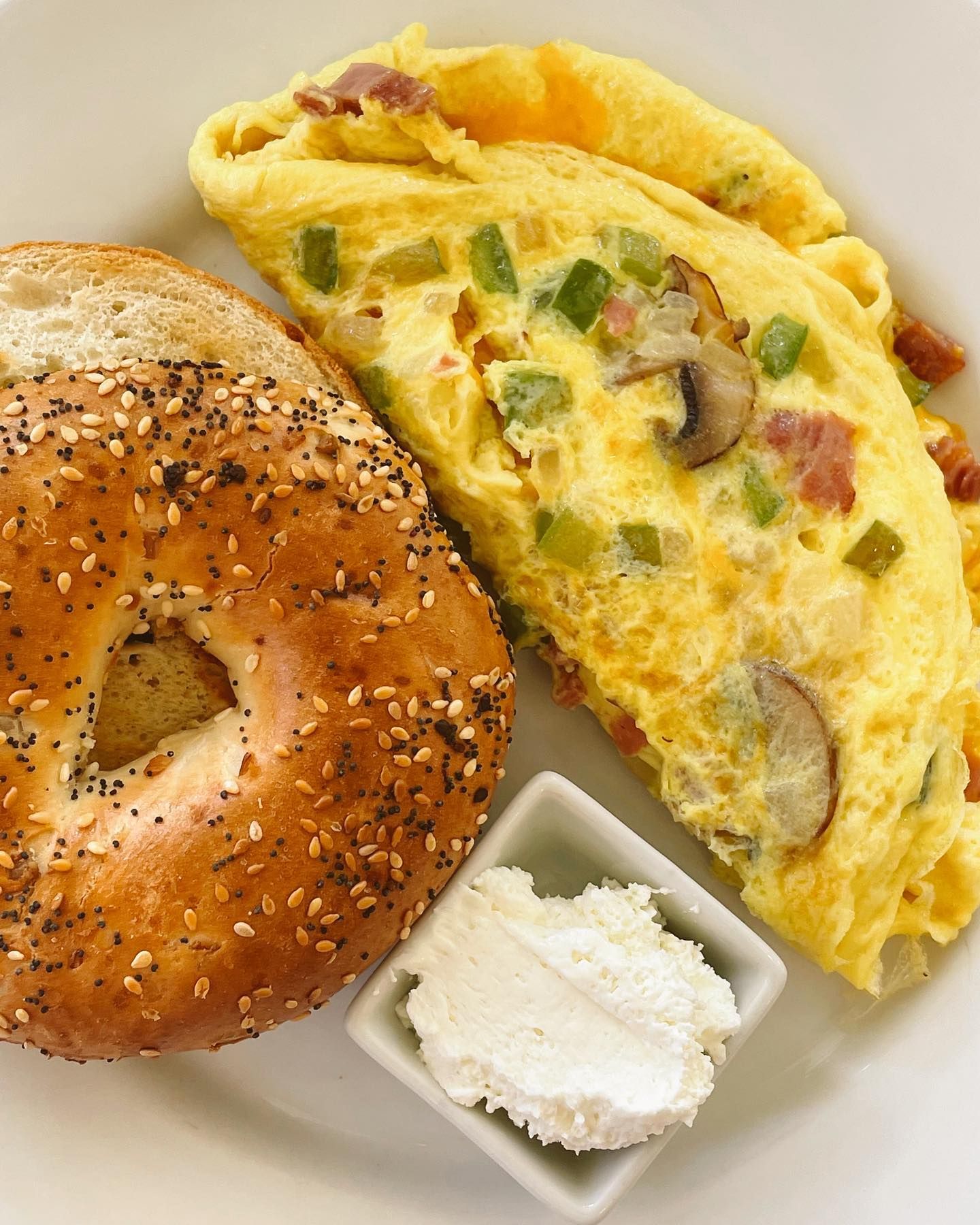 Omelette with vegetables and bacon, everything bagel, and cream cheese.