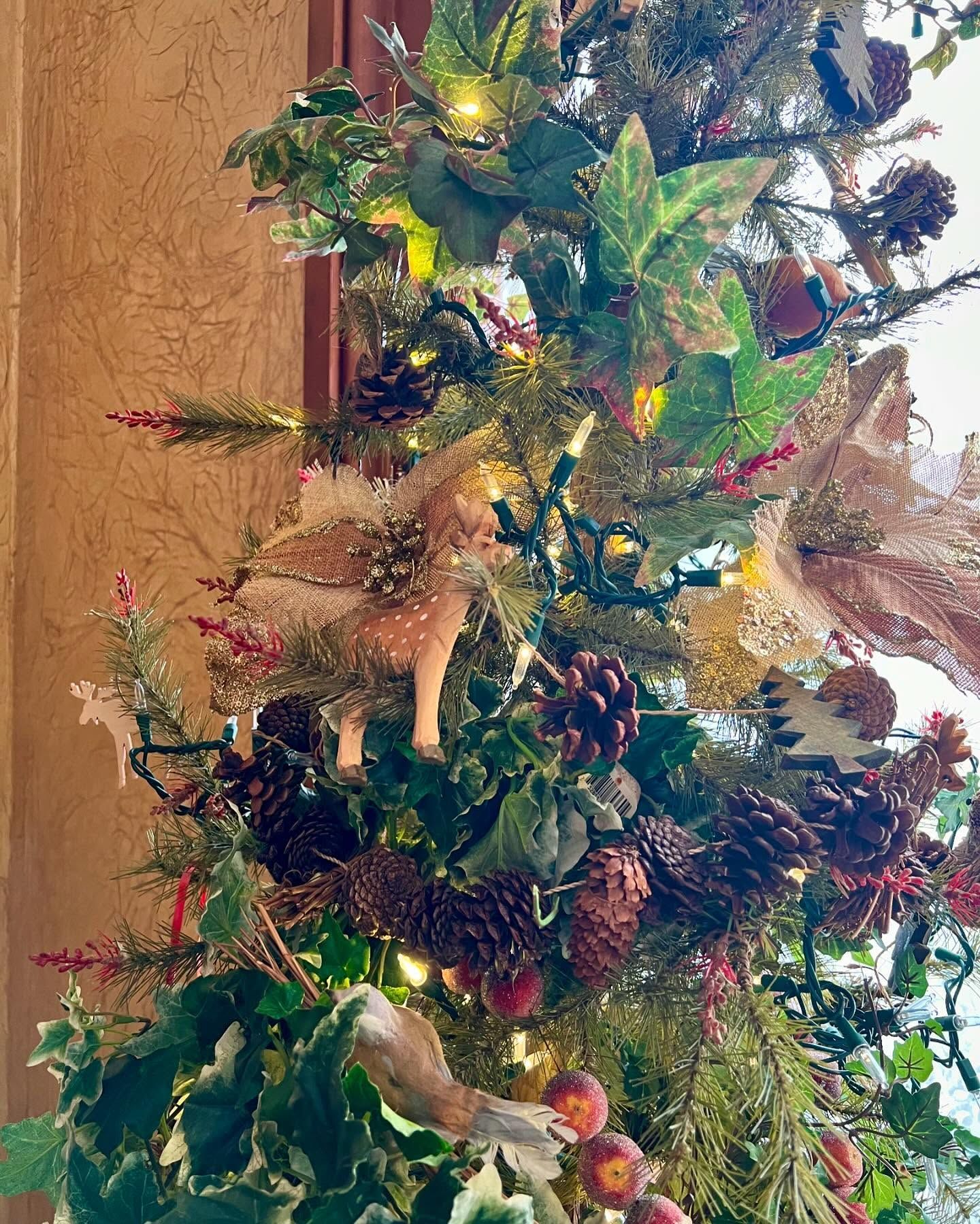Festive Christmas tree with ornaments: pine cones, fairy, and lights.
