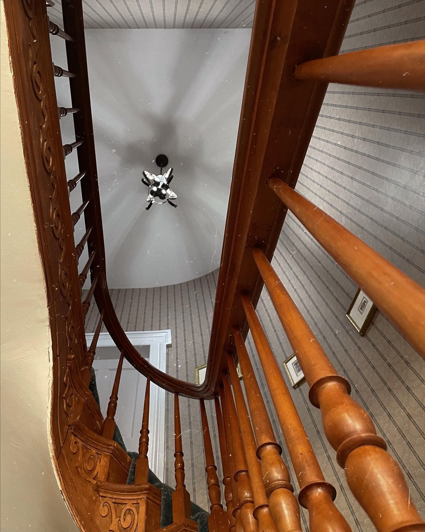 Wooden staircase with ornate banister and curved railing.