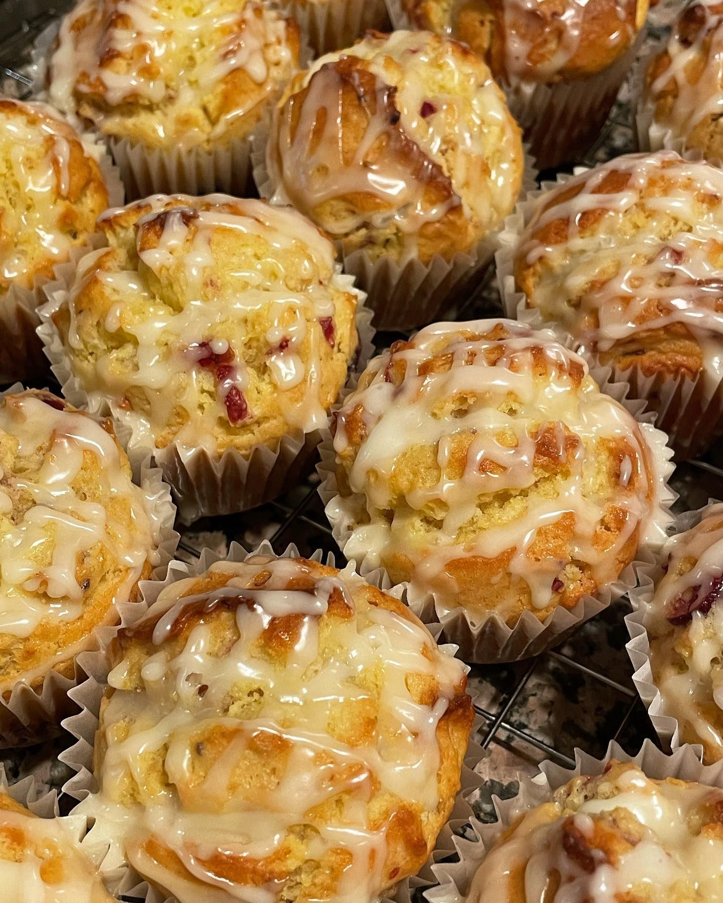 Close-up of glazed muffins in paper liners, arranged on a wire rack.