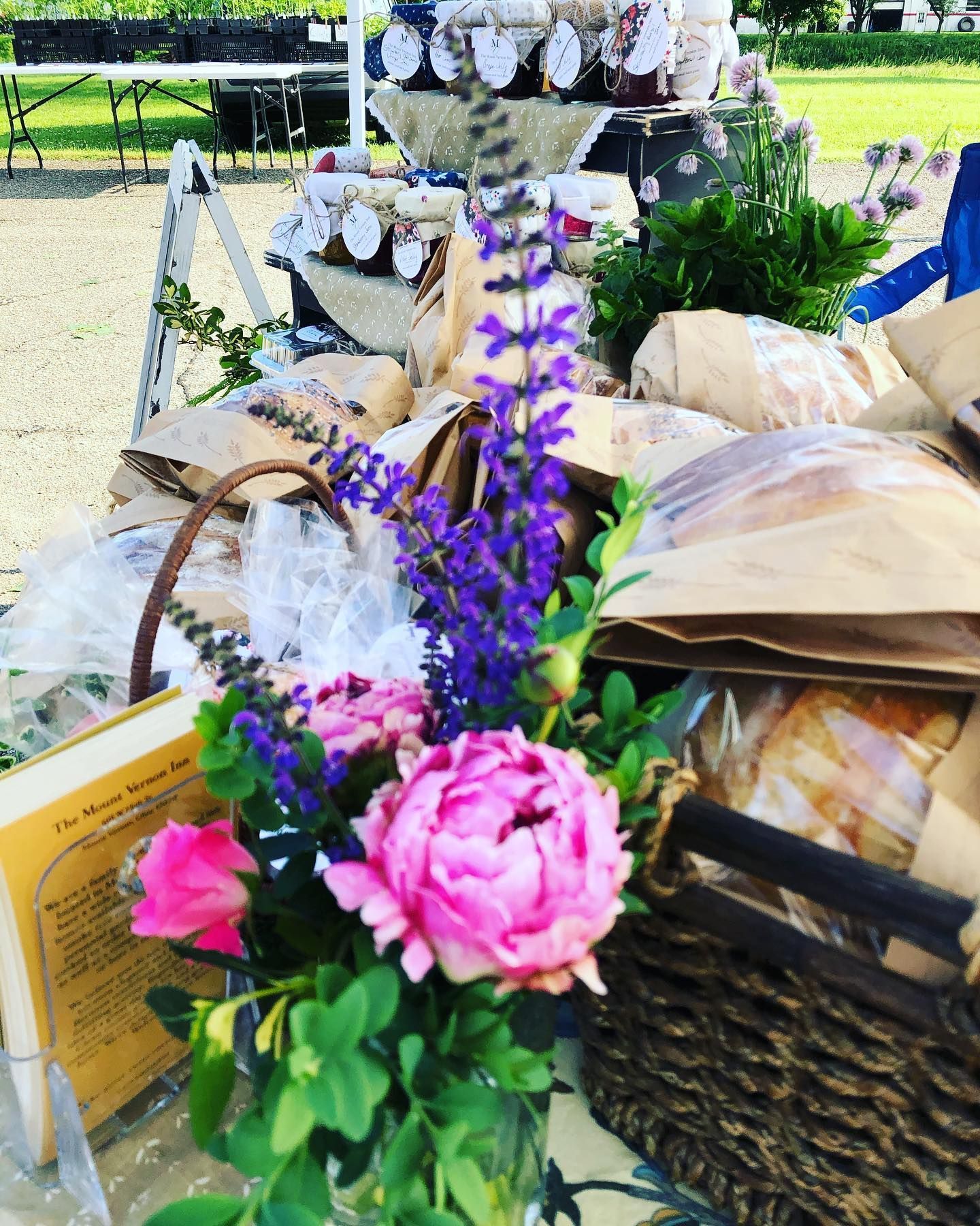 Farmers market display with flowers, bread, and jars of preserves.