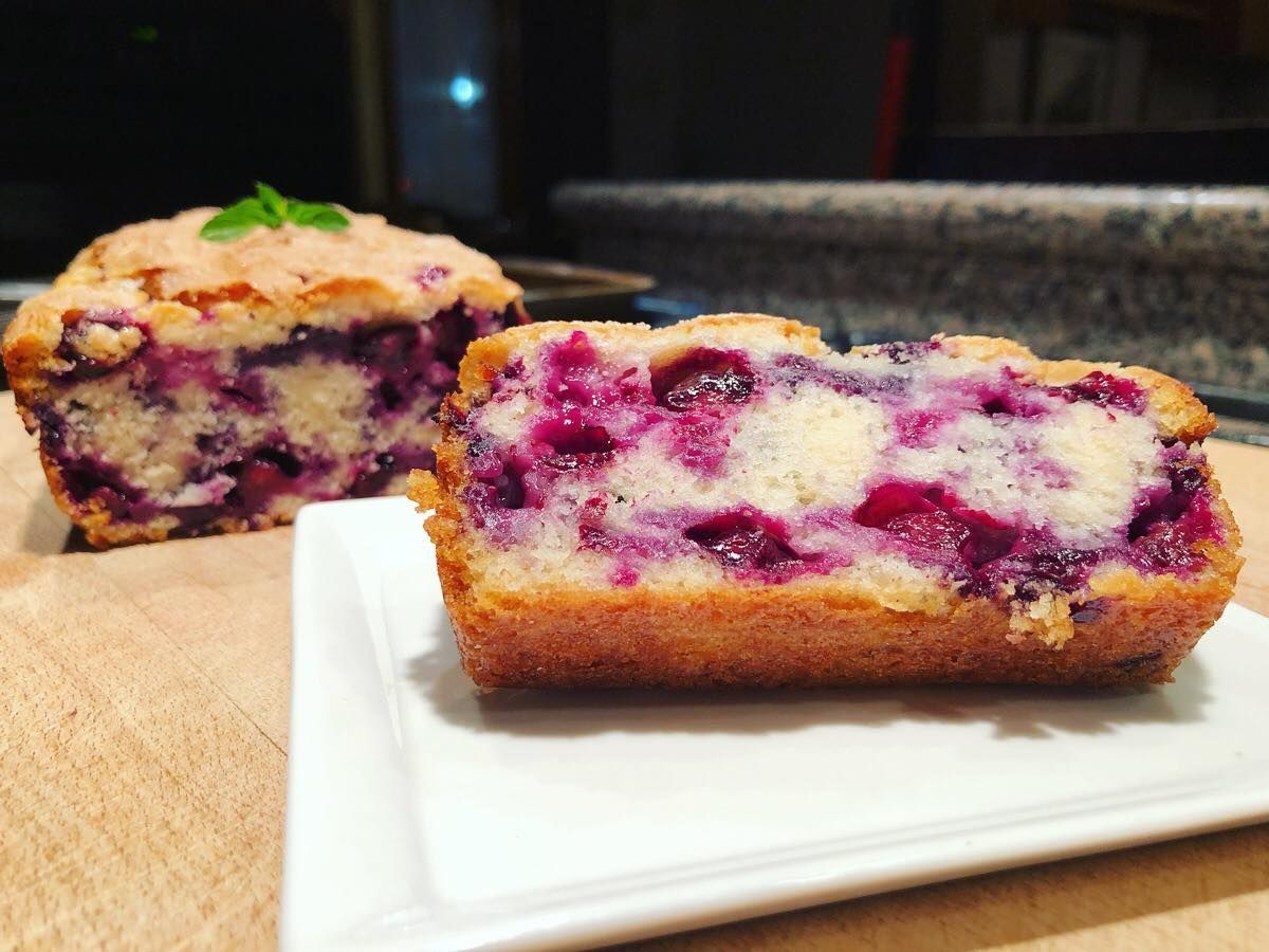 Blueberry loaf cake on white plate and wooden board.