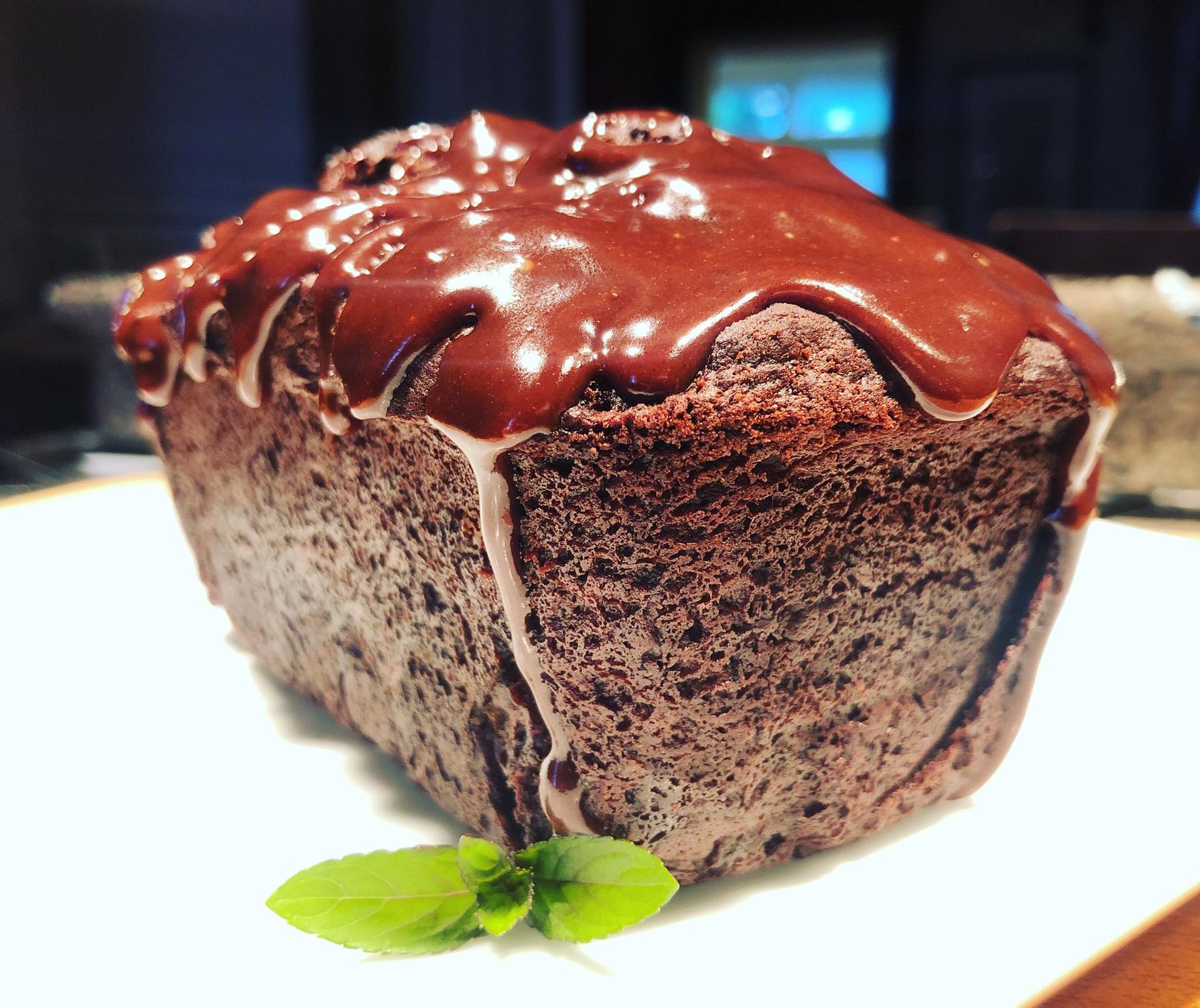 Chocolate loaf cake with chocolate glaze, garnished with mint leaf.