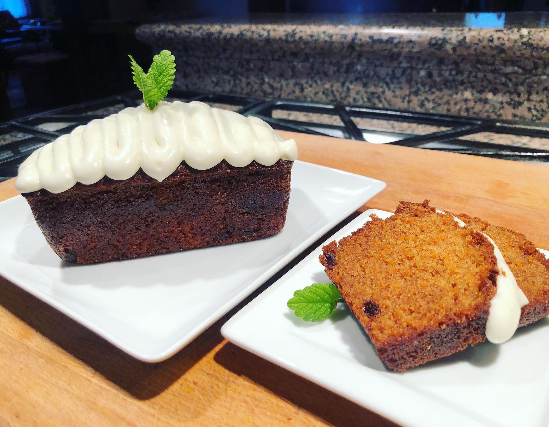 Mini loaf cake with white frosting and mint garnish, served on white plates.