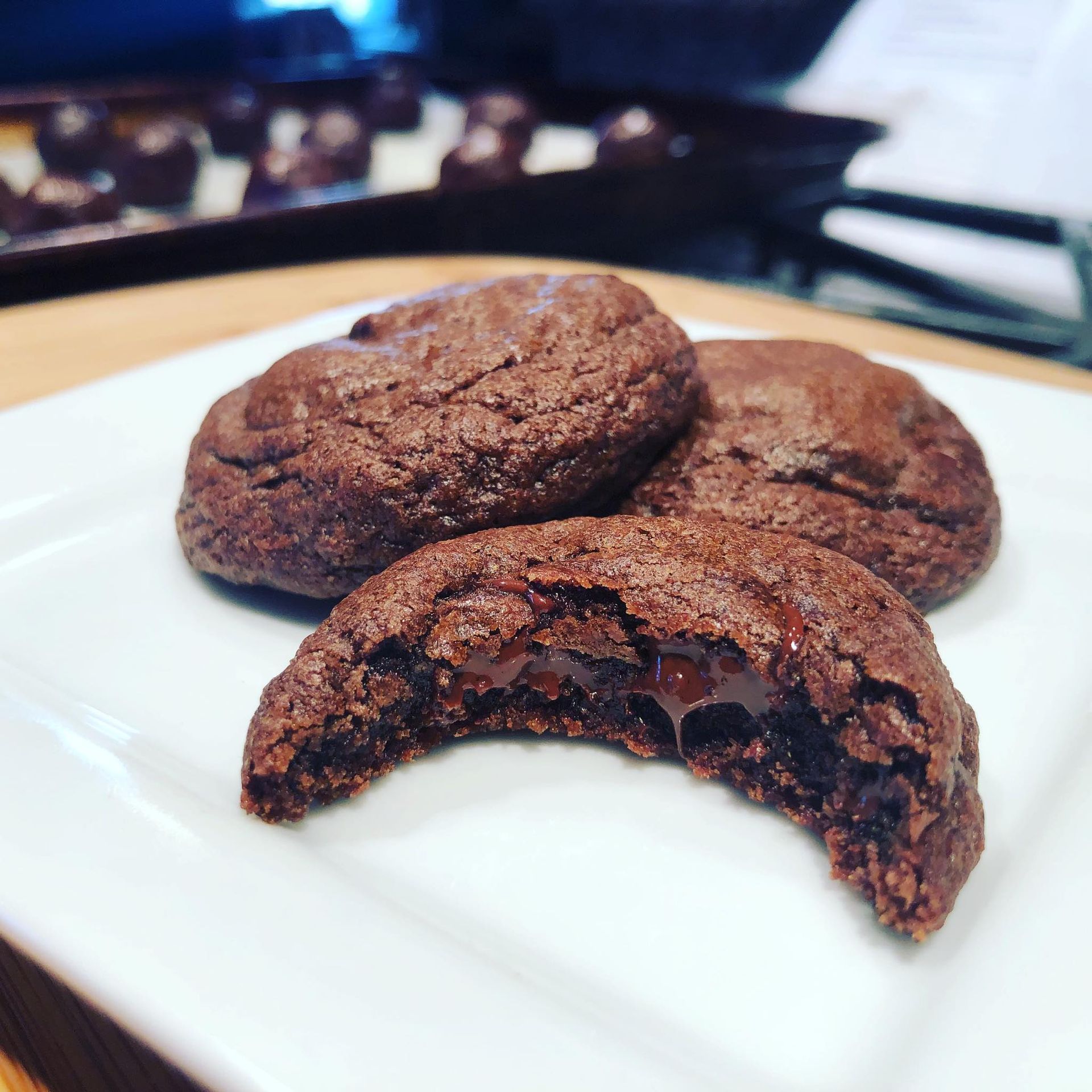 Chocolate cookies on a white plate, one broken open with melted chocolate visible.