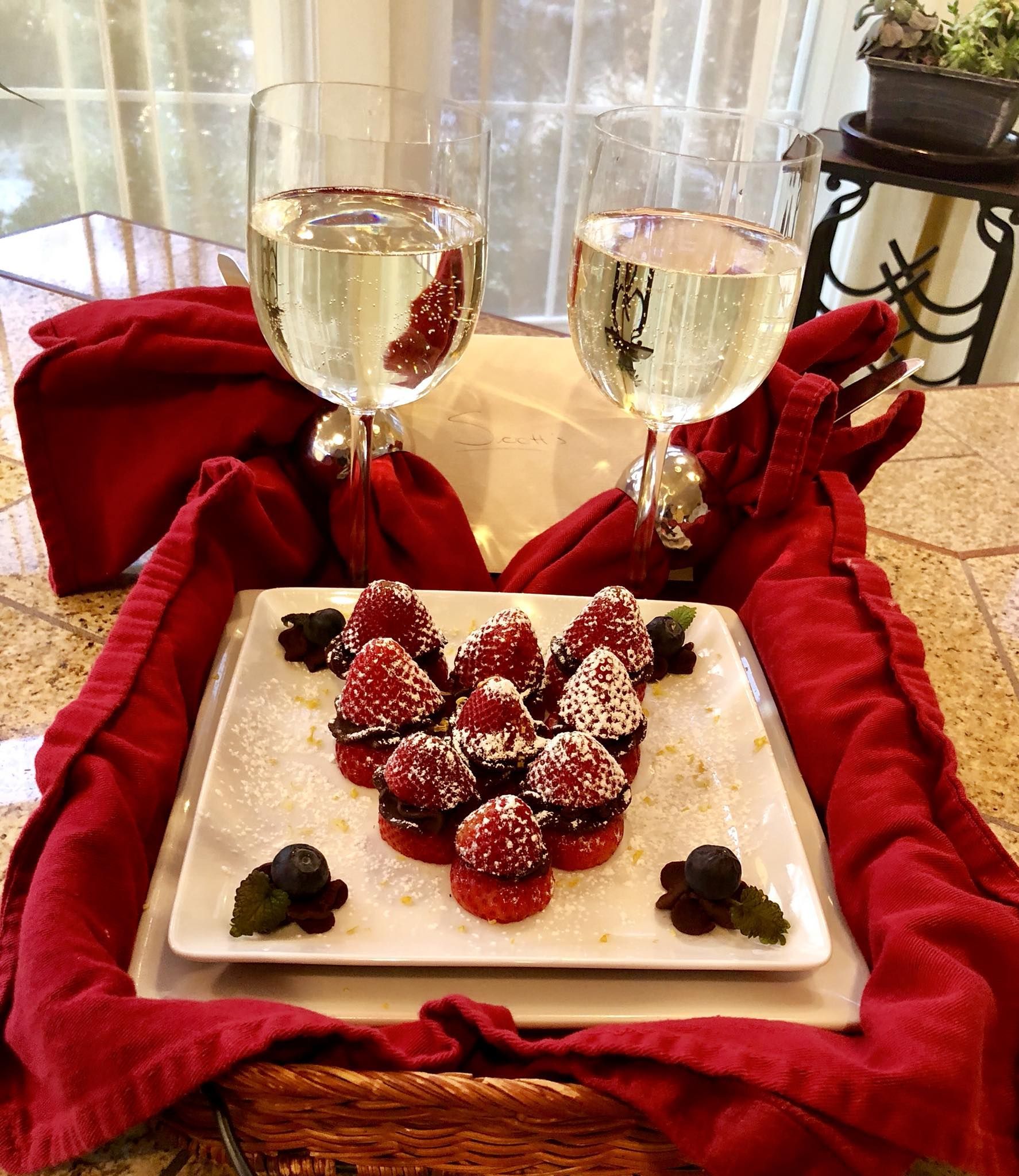 Two wine glasses, chocolate-covered strawberries, red napkin on a table.