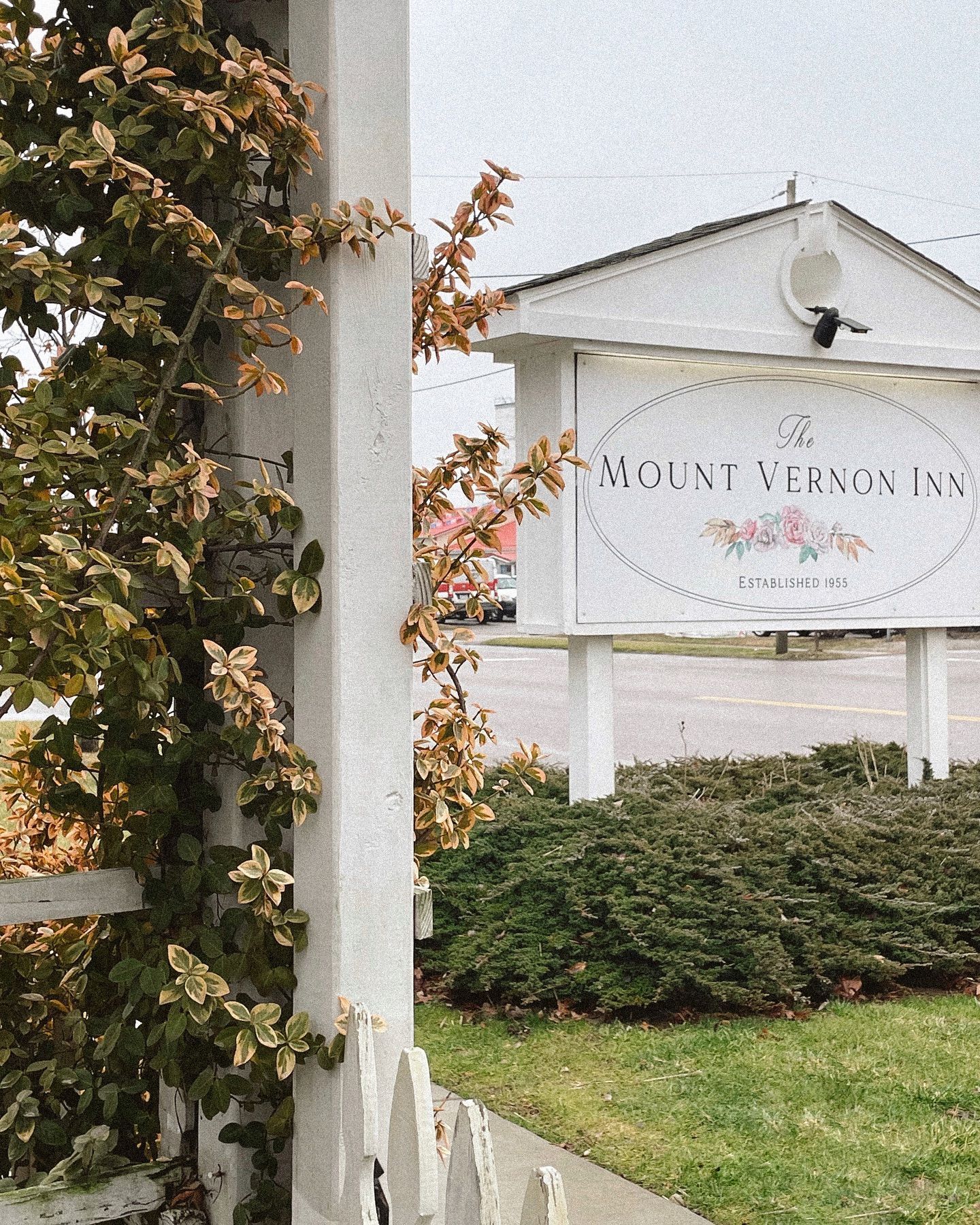 Sign for Mount Vernon Inn, with white picket fence, ivy, and shrubs.