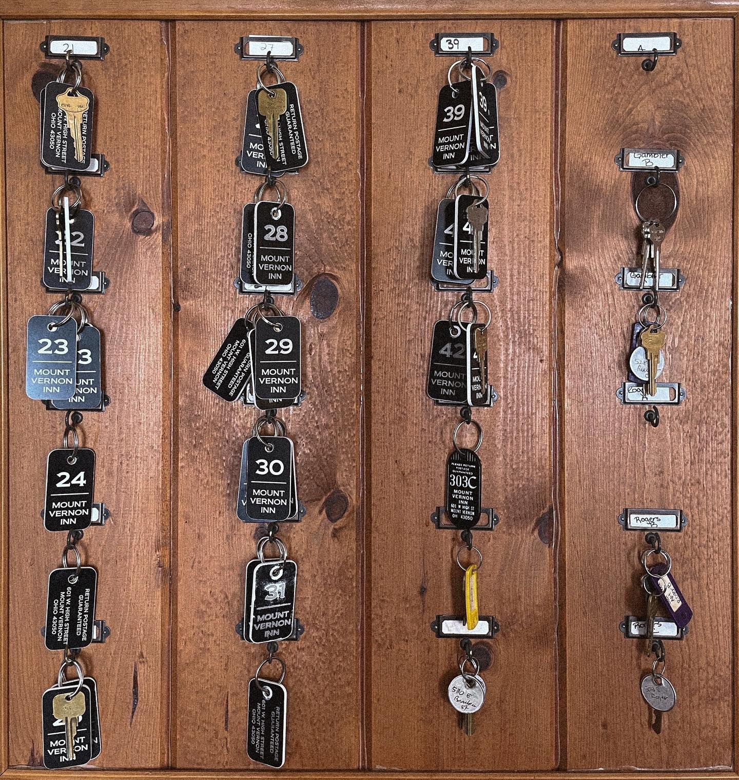Wooden key rack with numbered key tags hanging on hooks.