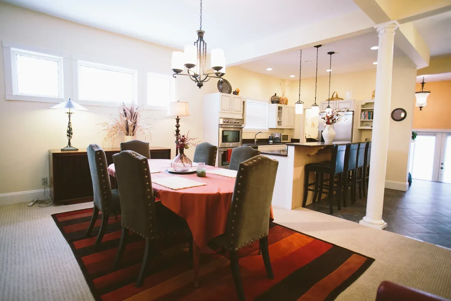 Dining room with a table set for eight, open to a kitchen with bar stools.