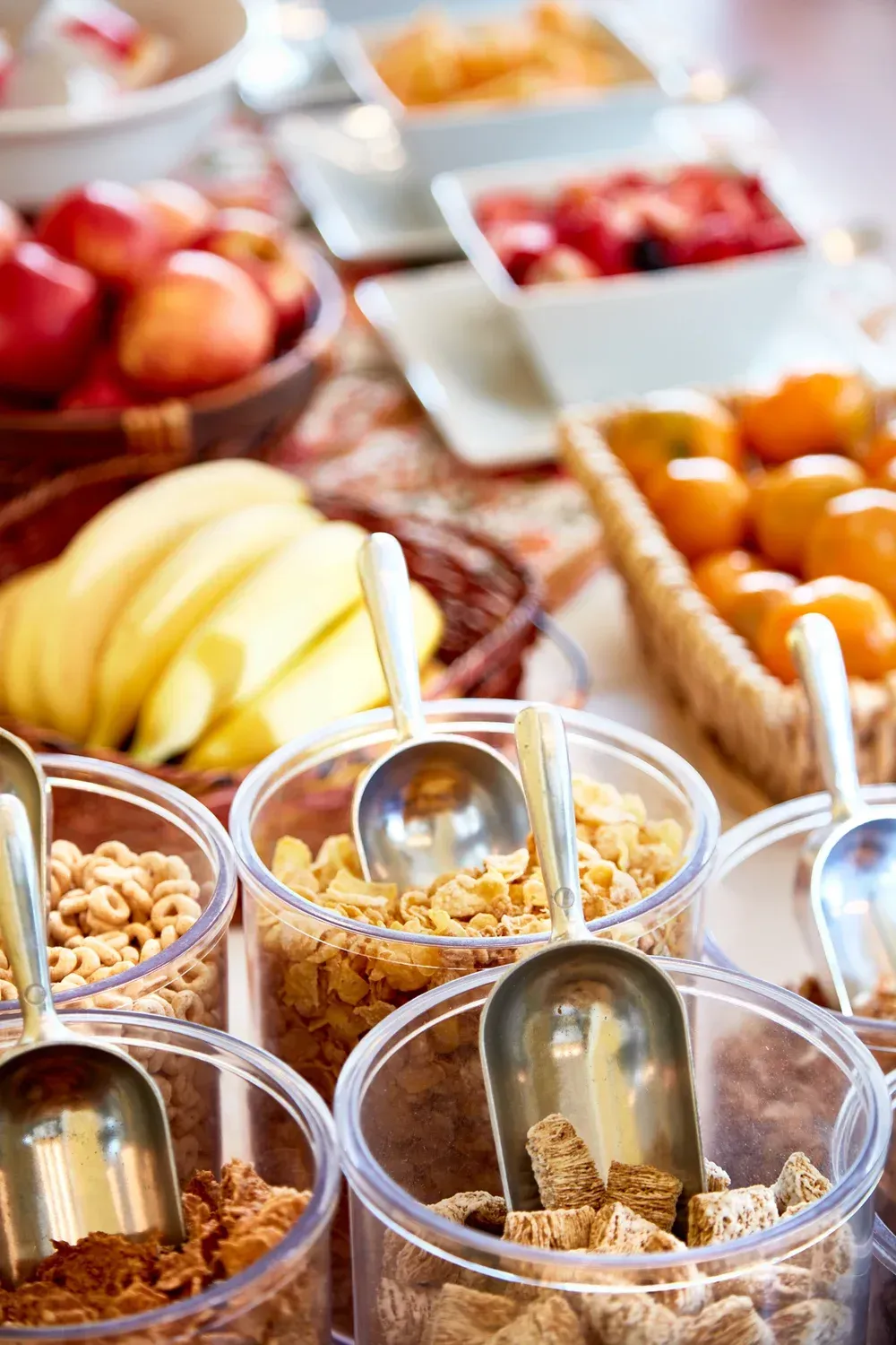 Breakfast buffet: cereal dispensers, fruits, and pastries.