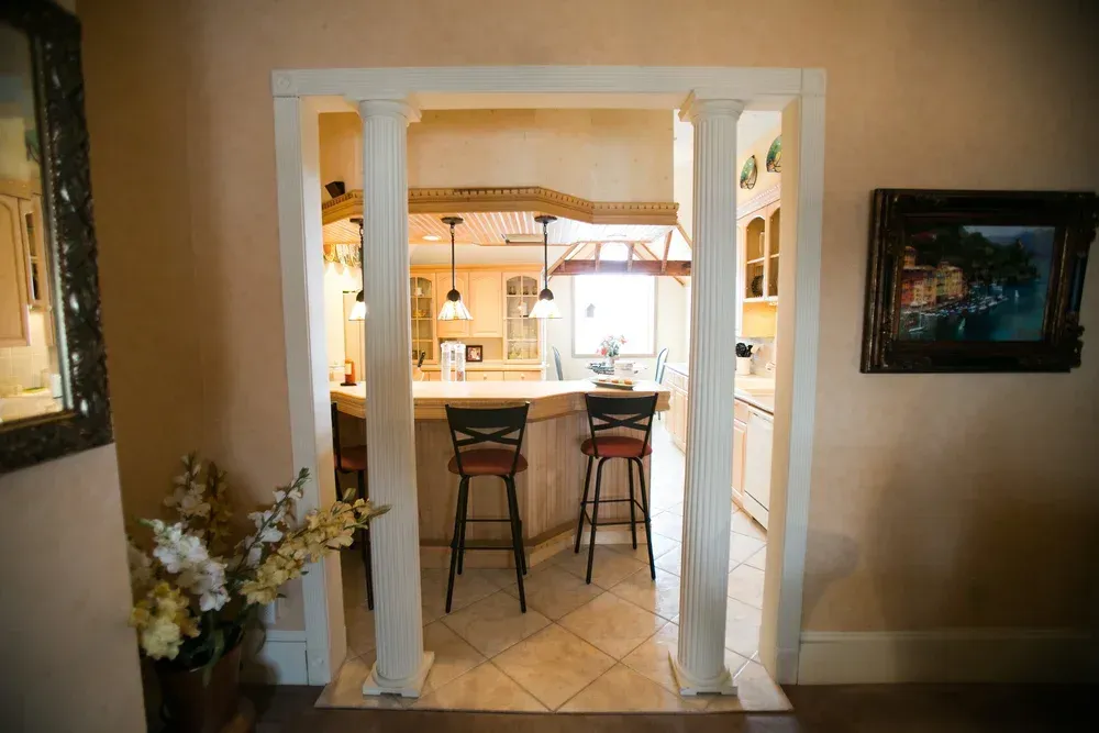 Archway leading to kitchen with bar stools.