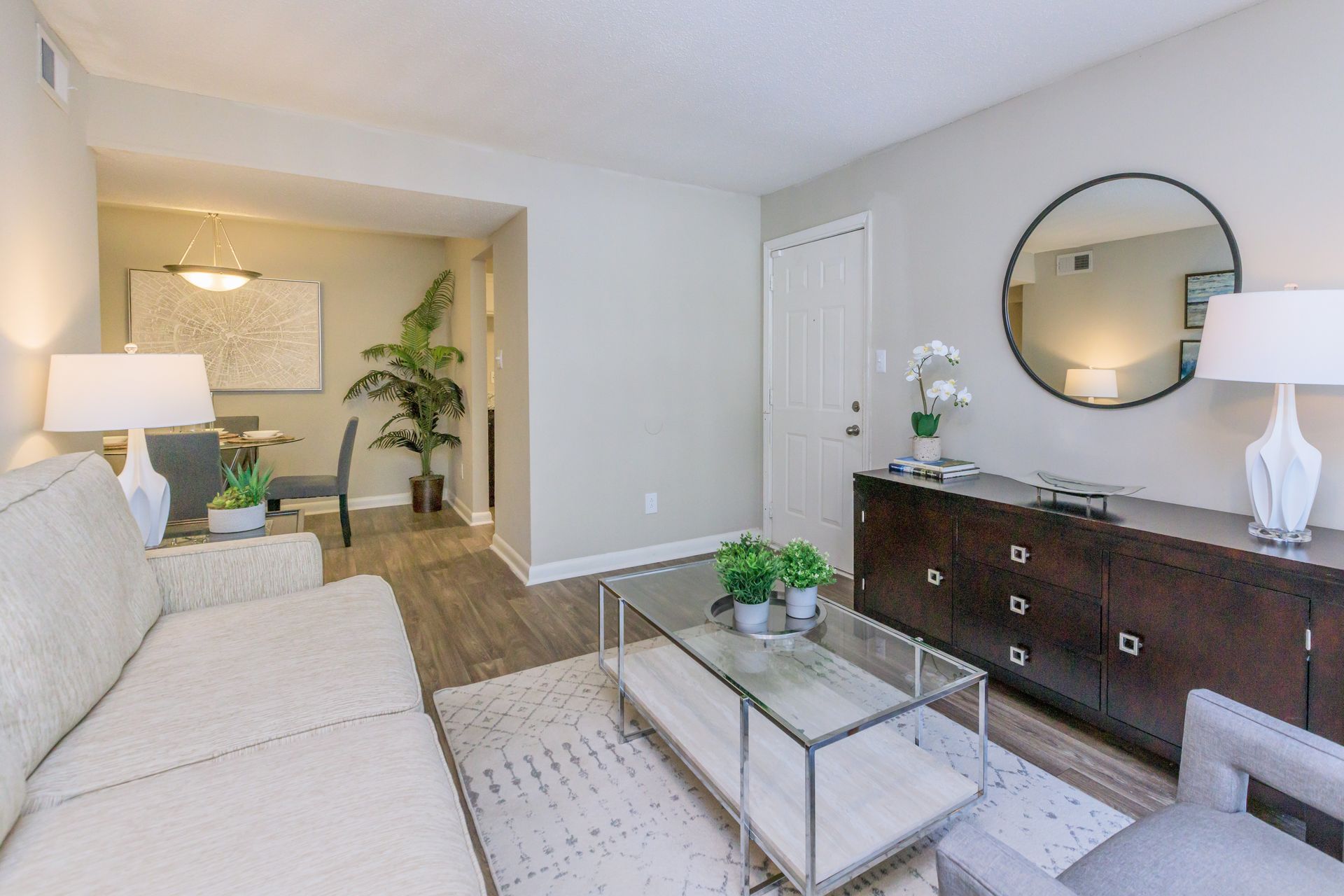 A living room with a couch , coffee table , dresser and mirror.