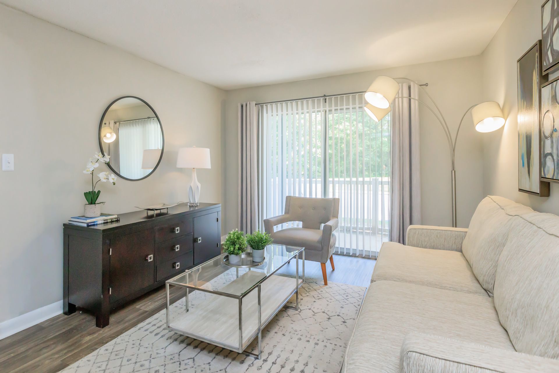 A living room with a couch , chair , coffee table and mirror.