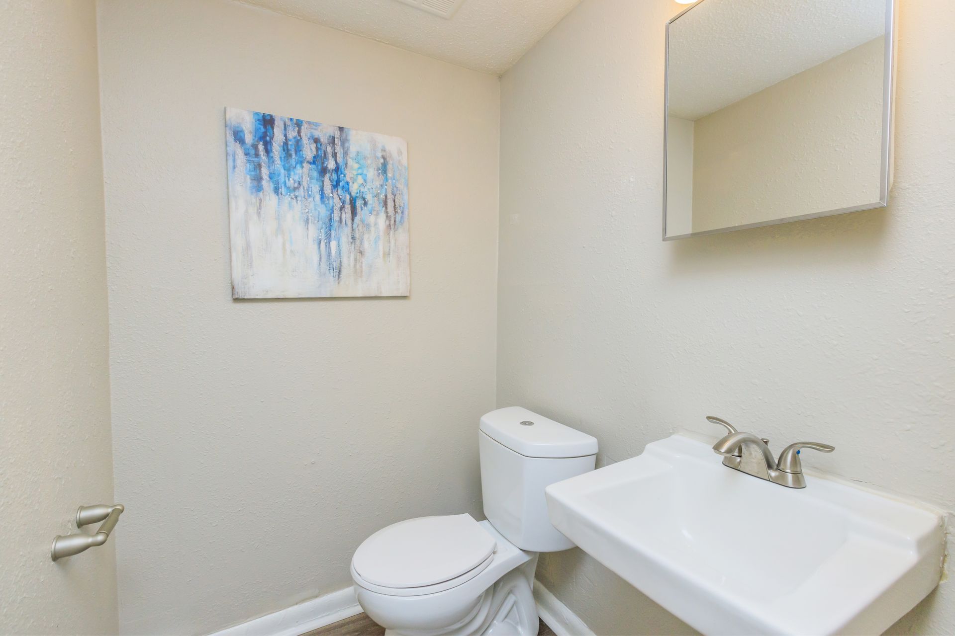 A bathroom with a toilet , sink and mirror.