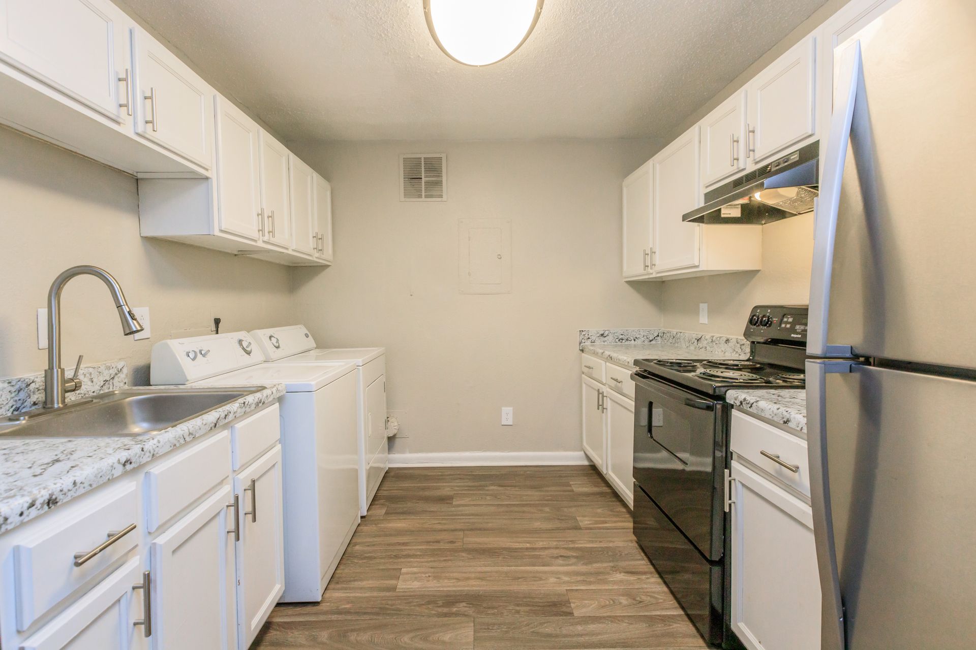 A kitchen with white cabinets , stainless steel appliances , a sink , and a refrigerator.