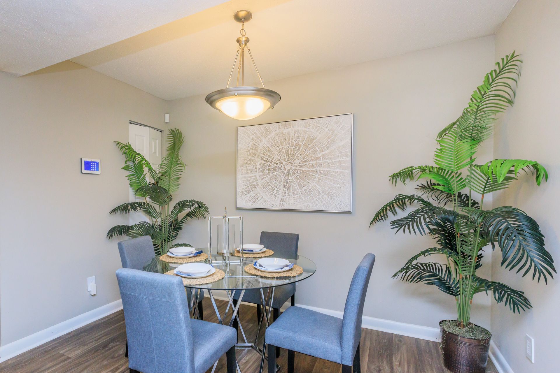 A dining room with a table and chairs and a potted plant.