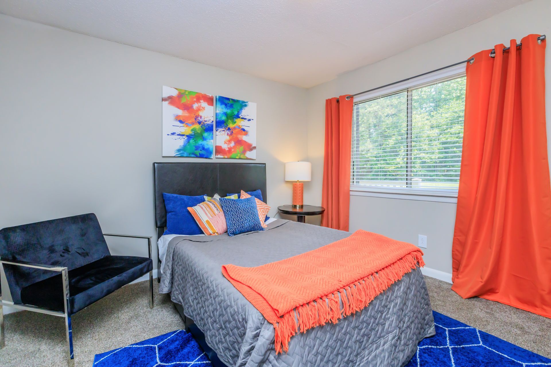 A bedroom with a bed , chair , rug and window.