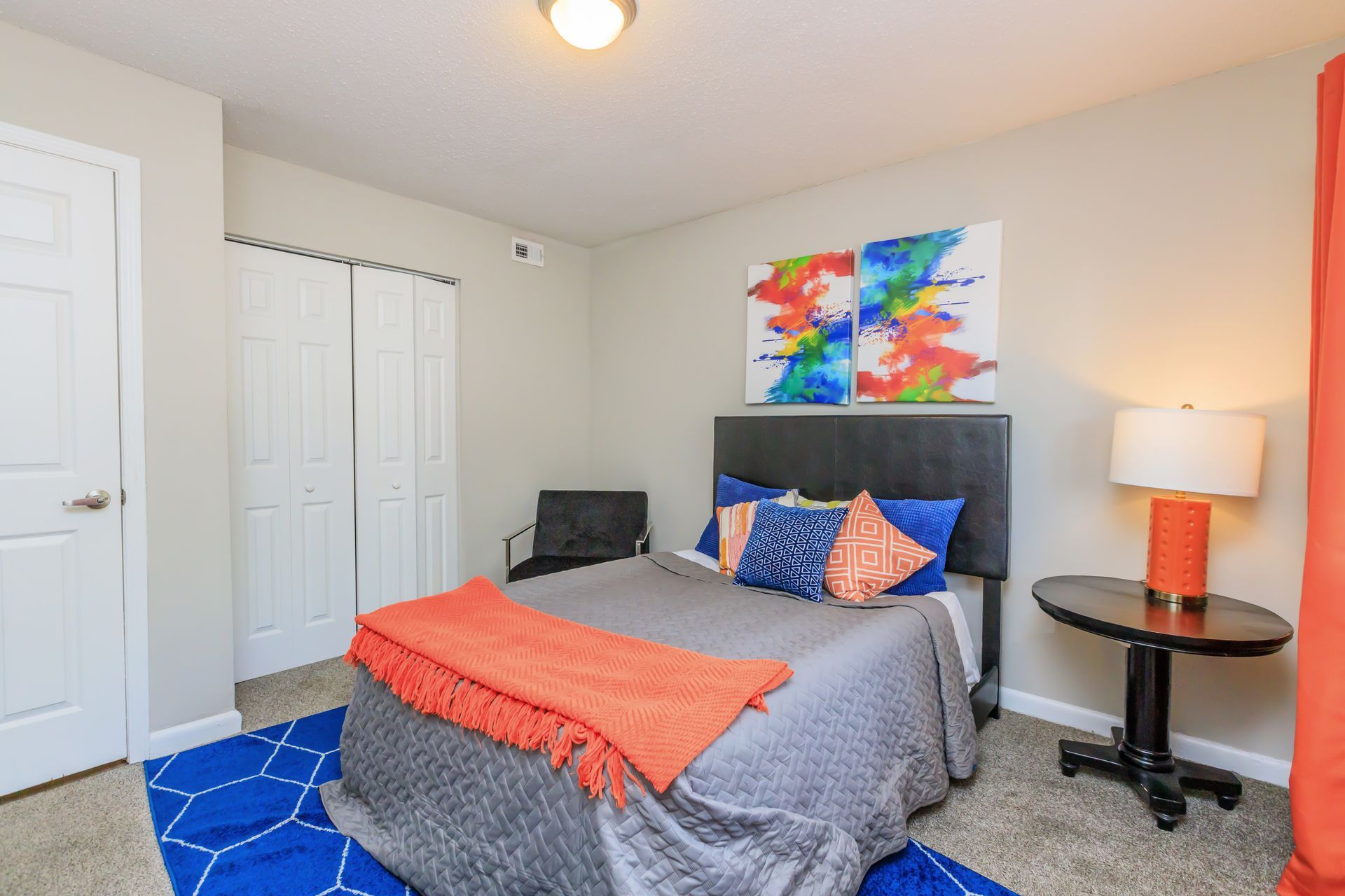 A bedroom with a bed , table , lamp and chair.